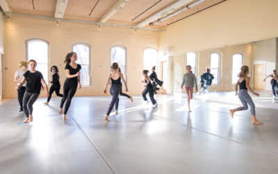 A group of dancers running around a studio.