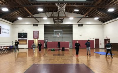 A group of people run inside a gym.