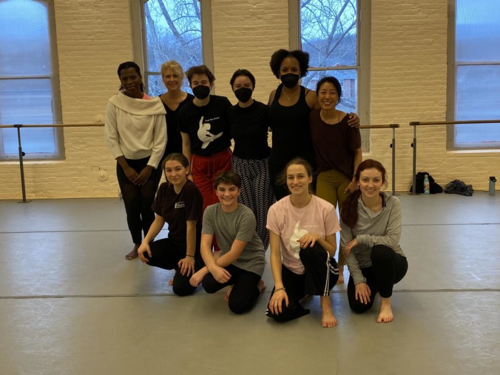 A group of dancers pose for a photo in a studio.