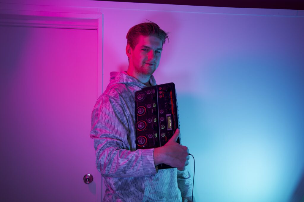 Galush holding a synthesizer with blue and pink lights on him.