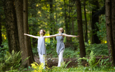 Two young dancers outside with arms outstretched and looking up