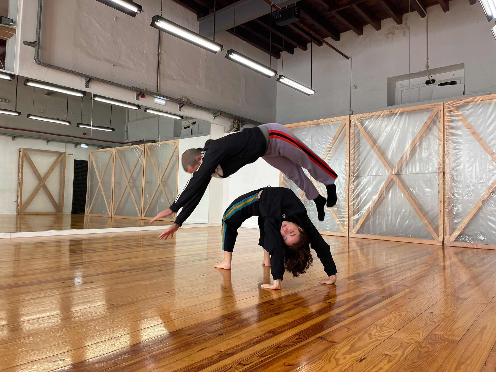 one dancer jumping over another dancer in a studio space