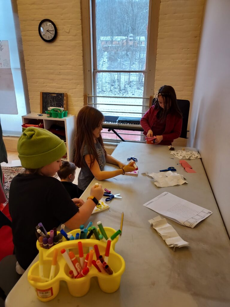 Three children sitting at a table doing arts and crafts