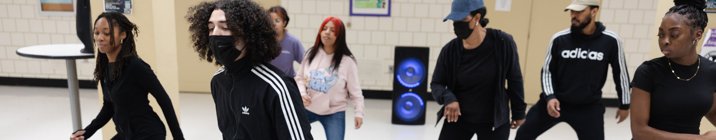 A group of artists teaching stepping in a high school classroom.